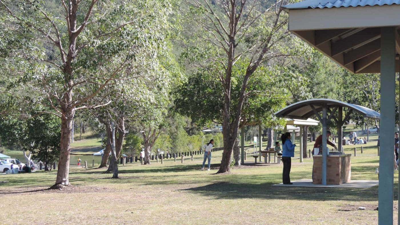 Covered barbecue shelters and picnic tables under tall gum trees at The Spit day-use area beside Lake Somerset